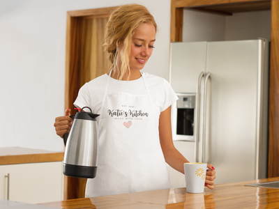 woman wearing personalized apron in kitchen pouring cup of coffee